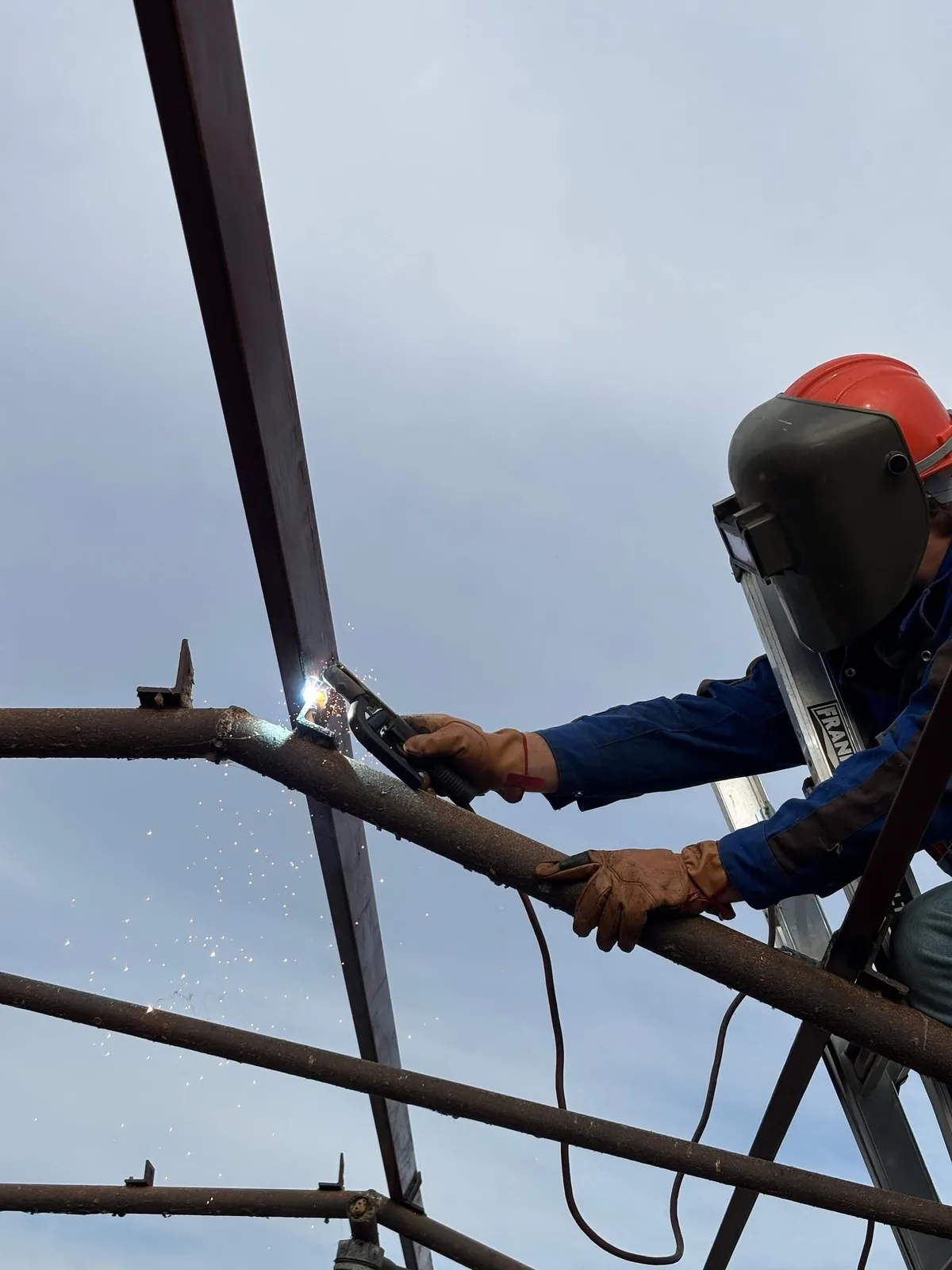 Welder repairing a steel frame at an active jobsite